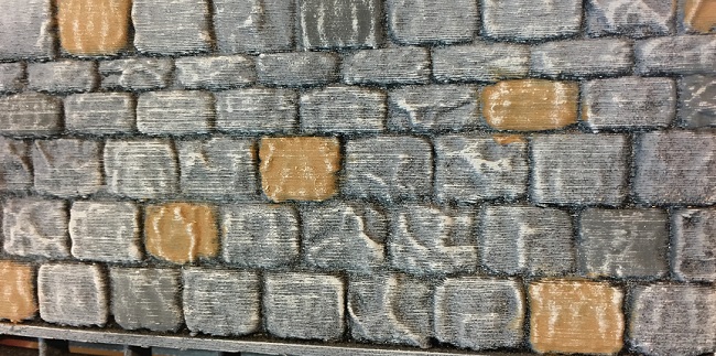 Close up of a 3D printed dungeon wall tile, printed with black PLA filament, showing the slight shininess between the bricks